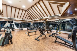 A modern gym with wooden beams, various exercise equipment, and large windows. - Ramada by Wyndham Kathmandu Dhumbarahi (Kathmandu)