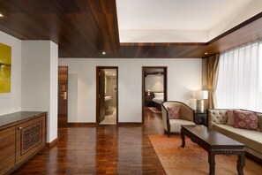 Amplia sala de estar con piso de madera, un sofá, una mesa de centro y un armario. Hay puertas que dan a otras habitaciones.