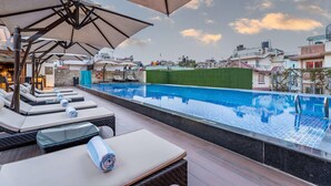 A rooftop pool area with lounge chairs, umbrellas, and a view of the cityscape. - Ramada by Wyndham Kathmandu Dhumbarahi (Kathmandu)