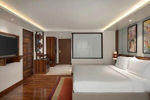 Una habitación de hotel moderna con una cama grande, un televisor de pantalla plana, muebles de madera y obras de arte en las paredes.