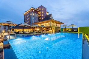 Un hotel con piscina, tumbonas, sombrillas y una zona de bar.