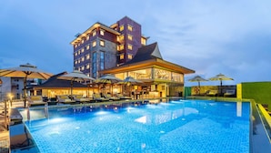 A hotel with a swimming pool, sun loungers, umbrellas, and a bar area. - Ramada by Wyndham Kathmandu Dhumbarahi (Kathmandu)