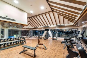 A gym with wooden beams, exercise equipment, and a mirrored wall. - Ramada by Wyndham Kathmandu Dhumbarahi (Kathmandu)