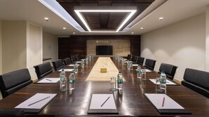 A conference room with a long table, black leather chairs, water bottles, and a projector screen. - Ramada by Wyndham Kathmandu Dhumbarahi (Kathmandu)