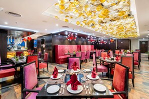 Un restaurante con asientos tapizados en rojo, mesas negras y un techo con una lámpara única.