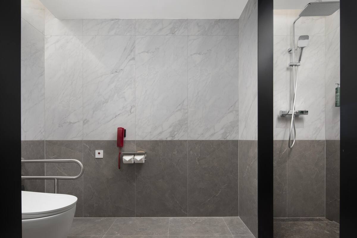 A modern bathroom with a shower, toilet, and hand dryer.