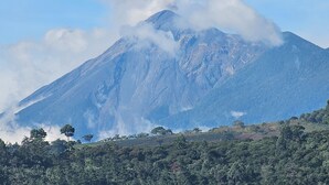 A mountain with a peak partially obscured by clouds, surrounded by dense forest. - San Carlos I House (Antigua Guatemala)