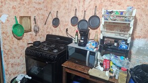A kitchen with a stove, pots, a coffee maker, and a shelf with various items. - San Carlos I House (Antigua Guatemala)