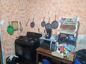 Une cuisine équipée d’une cuisinière, de casseroles, d’une machine à café et d’une étagère contenant divers objets.