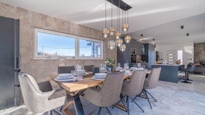 A modern dining area with a wooden table set for six, surrounded by grey upholstered chairs. - Jacuzzi and Sauna Villa (Labin)