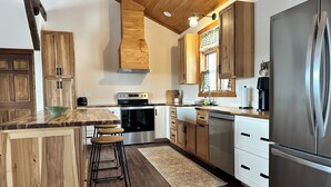 Eine moderne Küche mit Holzschränken, Edelstahlgeräten und einer zentralen Kochinsel mit Barhocker.