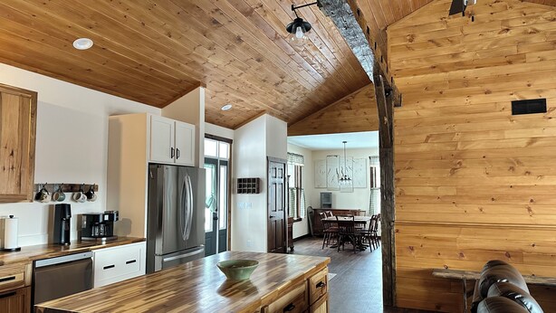 Eine moderne Küche mit Holzschränken, einer großen Kochinsel und einem Essbereich mit Tisch und Stühlen.