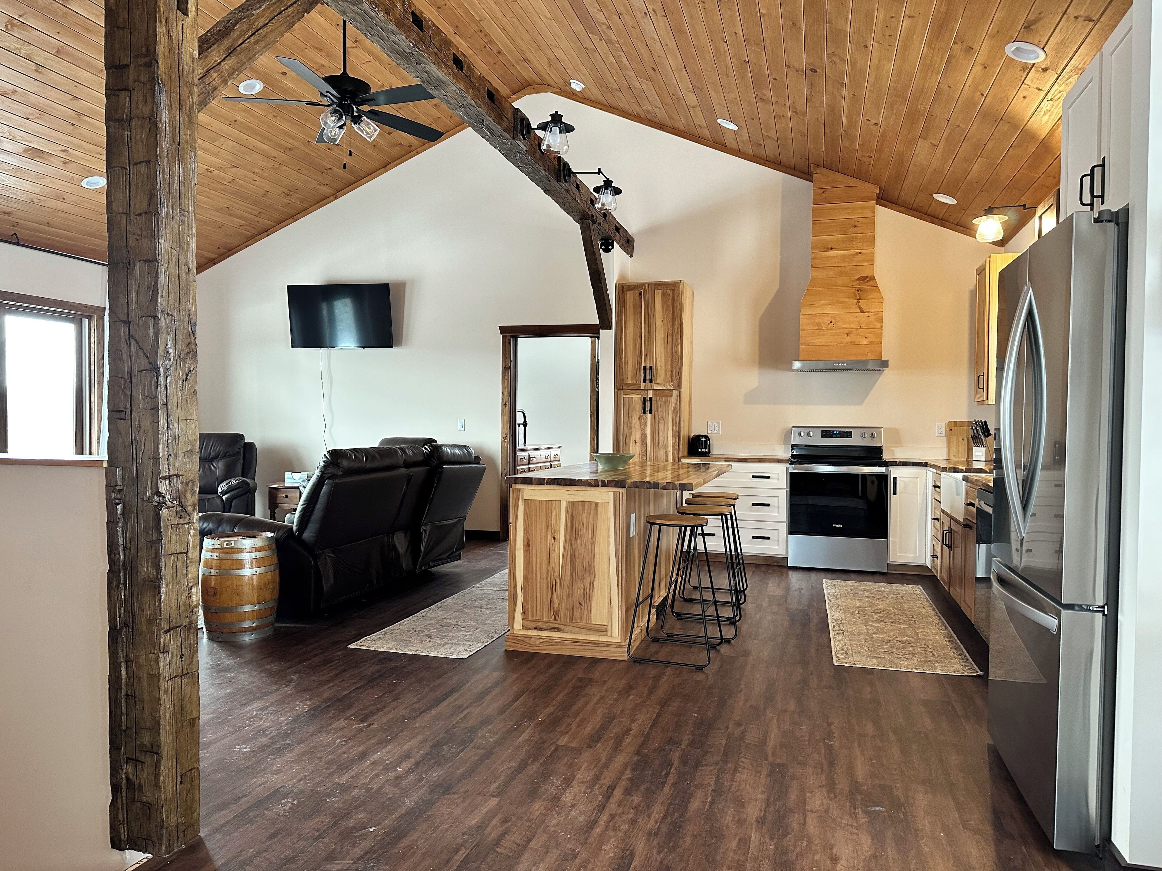 A spacious kitchen with wooden accents, a dining area with a leather couch, and a bar area with stools.