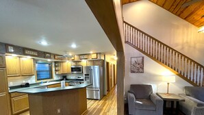 Eine moderne Küche mit Edelstahlgeräten, einer Holztischinsel und einem Essbereich mit Sofa und Tisch.