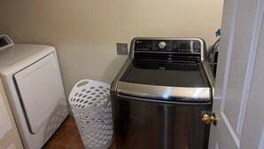 Een praktische wasruimte met een voorlader wasmachine en droger, een functionele ruimte met roestvrijstalen apparatuur en een witte wasmand.