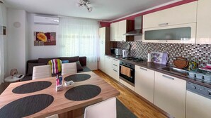 A compact kitchen with a dining area, featuring a microwave, toaster, kettle, and a tiled backsplash. - Cozy apartment in Gornji Karin with WiFi (Gornji Karin)