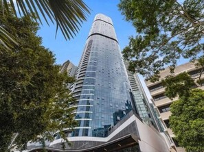Un grand bâtiment moderne, doté d’une partie supérieure incurvée et entouré d’arbres.