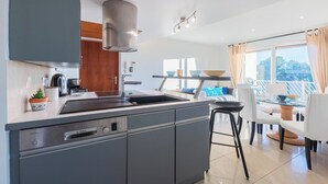 Een moderne keuken met een Bosch vaatwasser, een spoelbak en een eethoek met een glazen tafel en witte stoelen.