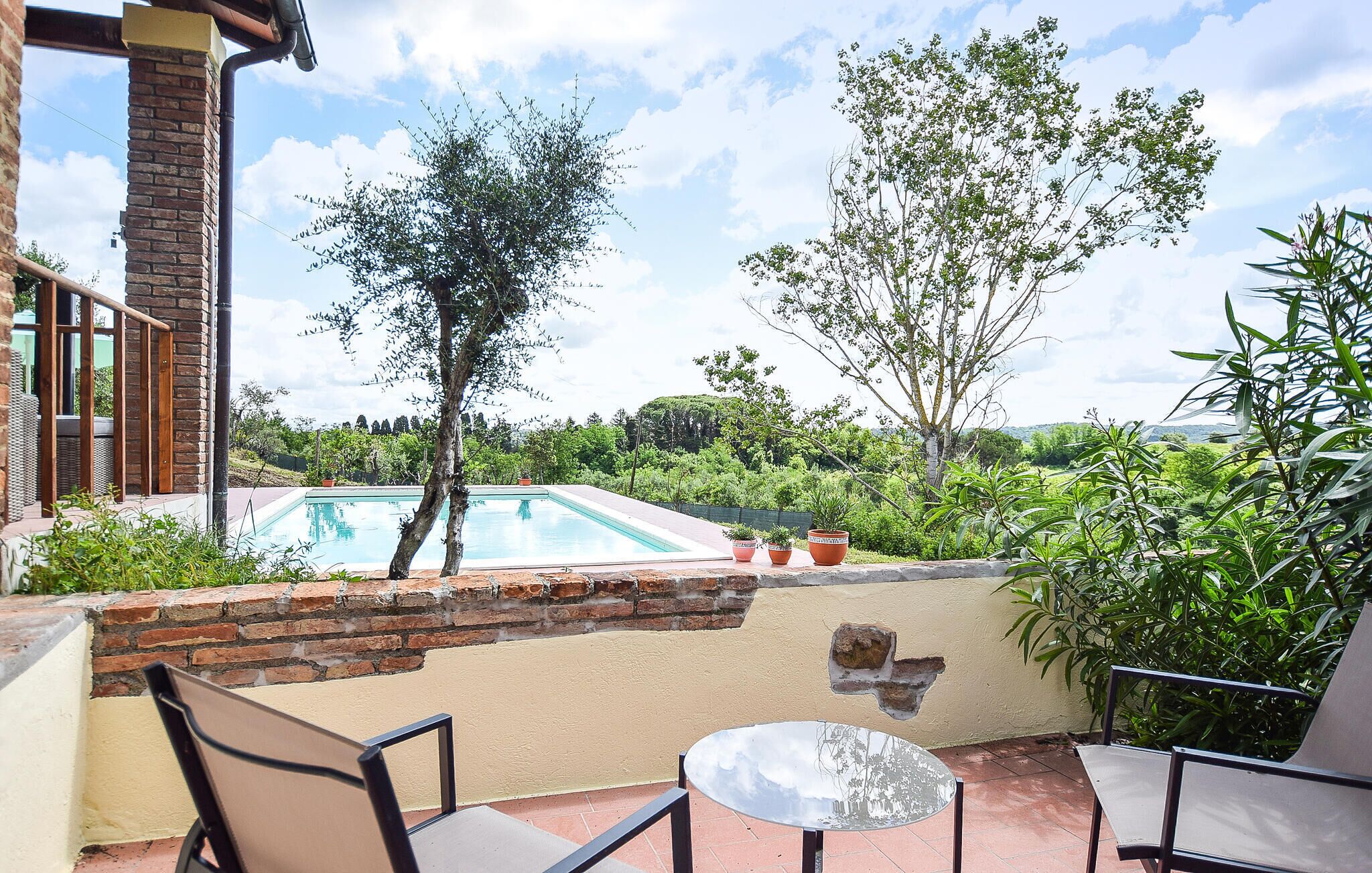 A patio with a pool, outdoor furniture, and a view of the surrounding greenery.