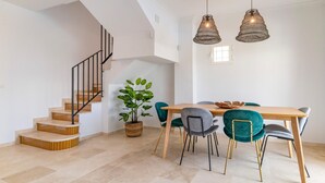 Un comedor moderno con una mesa de madera, sillas color turquesa y una escalera con escalones de madera.