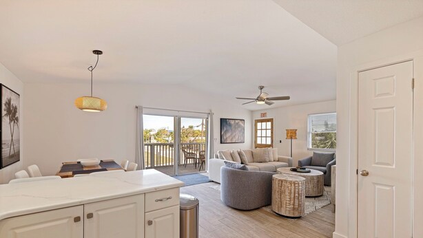 A spacious living area with a kitchen counter, dining table, and a balcony with a view.