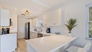 A modern kitchen with white cabinetry, a marble countertop, and a built-in island with seating.