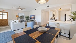 A modern living room with a dining area, a kitchen, and an exit sign.