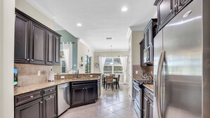 Una cocina moderna con armarios oscuros, un refrigerador de acero inoxidable y una encimera de granito.