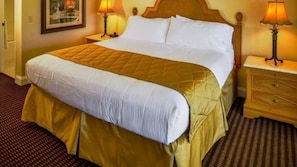 A hotel room with a large bed, two bedside tables, and a framed picture on the wall.