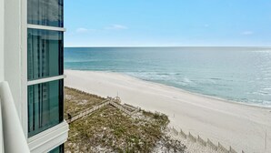 A view of a beach from a building with large windows overlooking the ocean. - Palacio 902 | Beachfront & Resort Amenities | My Beach Getaways (Pensacola)