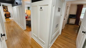 A hallway with white doors, a wooden floor, and a television in the corner. - The BlueStone-Stylish 3BR in Central Abilene (Abilene)