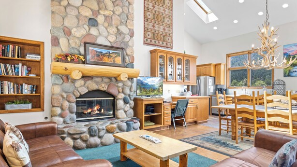 Una sala de estar acogedora con chimenea de piedra, sofás de cuero, una mesa de centro de madera y una estantería.