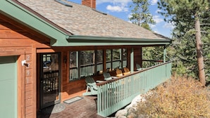 Eine Holzhütte mit Veranda, nummerierten Türen und Sitzgelegenheiten im Freien.