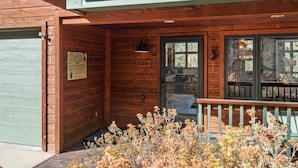 Ein hölzernes Chalet mit einer grünen Garagentür, einem Willkommensschild und der Nummer 2291 an der Tür.