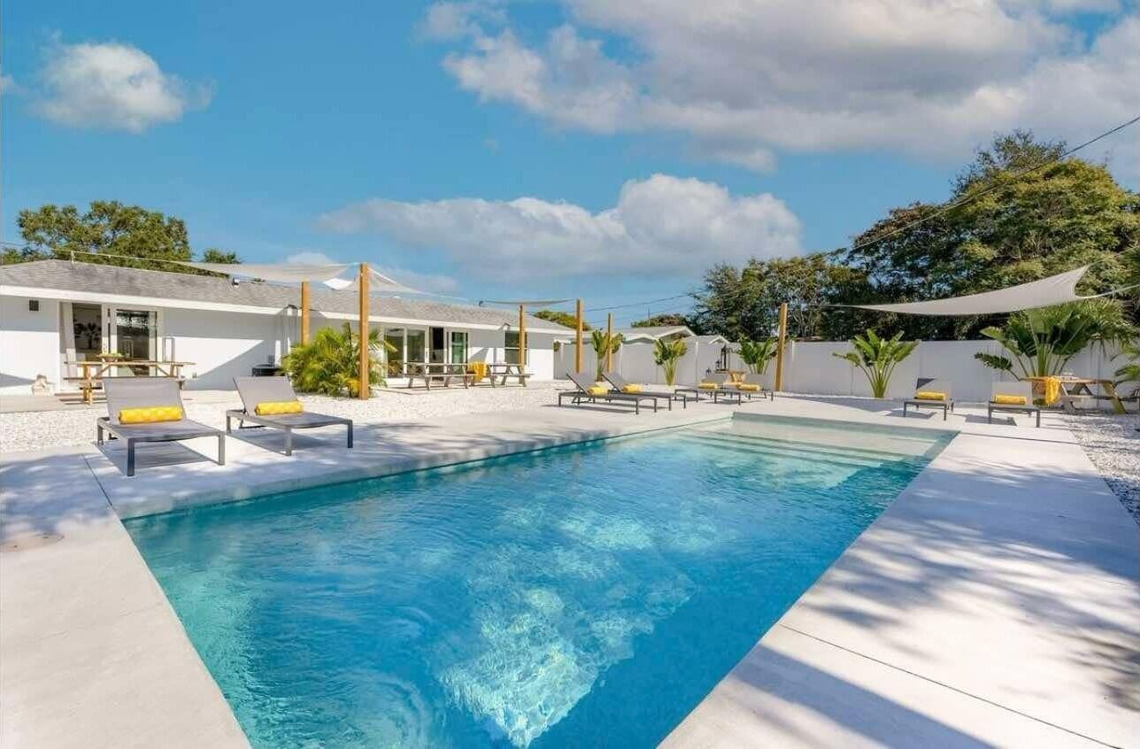 Piscina con sillones de descanso y un área de patio techada.