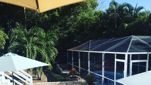 Eine überdachte Terrasse mit Glasverkleidung, einem Pool und Gartenmöbeln.