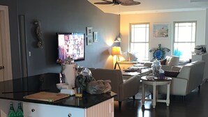 Ein geräumiger Wohnbereich mit Kücheninsel, Deckenventilator und Fernseher.