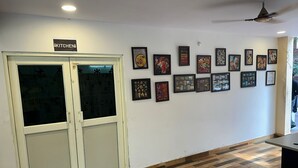 A room with a kitchen sign, a wooden floor, and a wall with framed pictures. - Hotel Star Inn (Visakhapatnam)