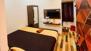 A hotel room with a bed, a TV mounted on the wall, a wardrobe, and a bathroom with a shower and toilet. - Hotel Star Inn (Visakhapatnam)