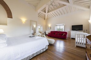 A bedroom with a bed, a red sofa, a TV, and a crib. - Villa Yvonne by MMega (Signa)