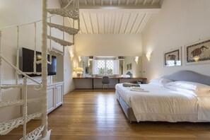 Un dormitorio con cama, escritorio, silla, televisor y escalera.