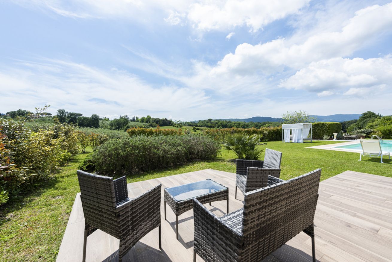 Eine Terrasse im Freien mit Korbmöbeln, einem Pool und Blick auf die Landschaft.