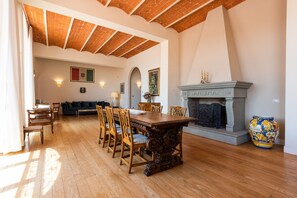 A dining area with a wooden table and chairs, a fireplace, and a sofa in the background. - Villa Yvonne by MMega (Signa)