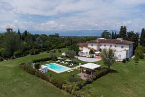 Una casa grande con piscina, jardín y vistas a las montañas.