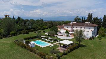 A large house with a swimming pool, garden, and a view of mountains.