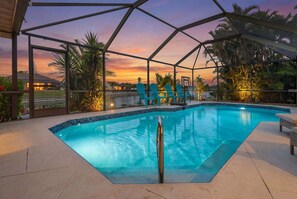 Ein Swimmingpool mit Glasüberdachung, umgeben von Stühlen und Palmen.