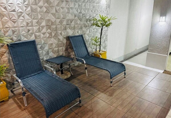 A waiting area with two blue woven chairs, a small table, and a potted plant.