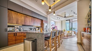 Een moderne keuken met een centraal eiland, houten kastjes en een roestvrijstalen prullenbak.