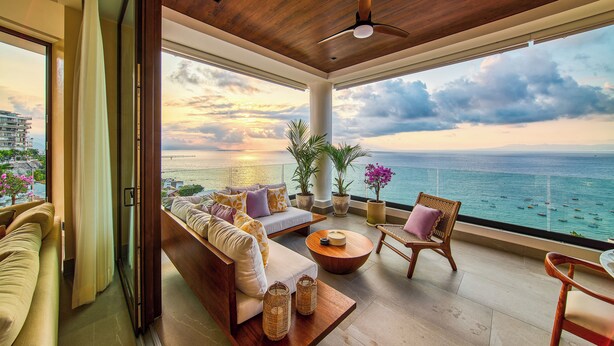 A spacious balcony with a wooden ceiling, a sofa, a chair, and a table. - Chic Penthouse Ocean Views, Rooftop Pool & Balcony (Puerto Vallarta)