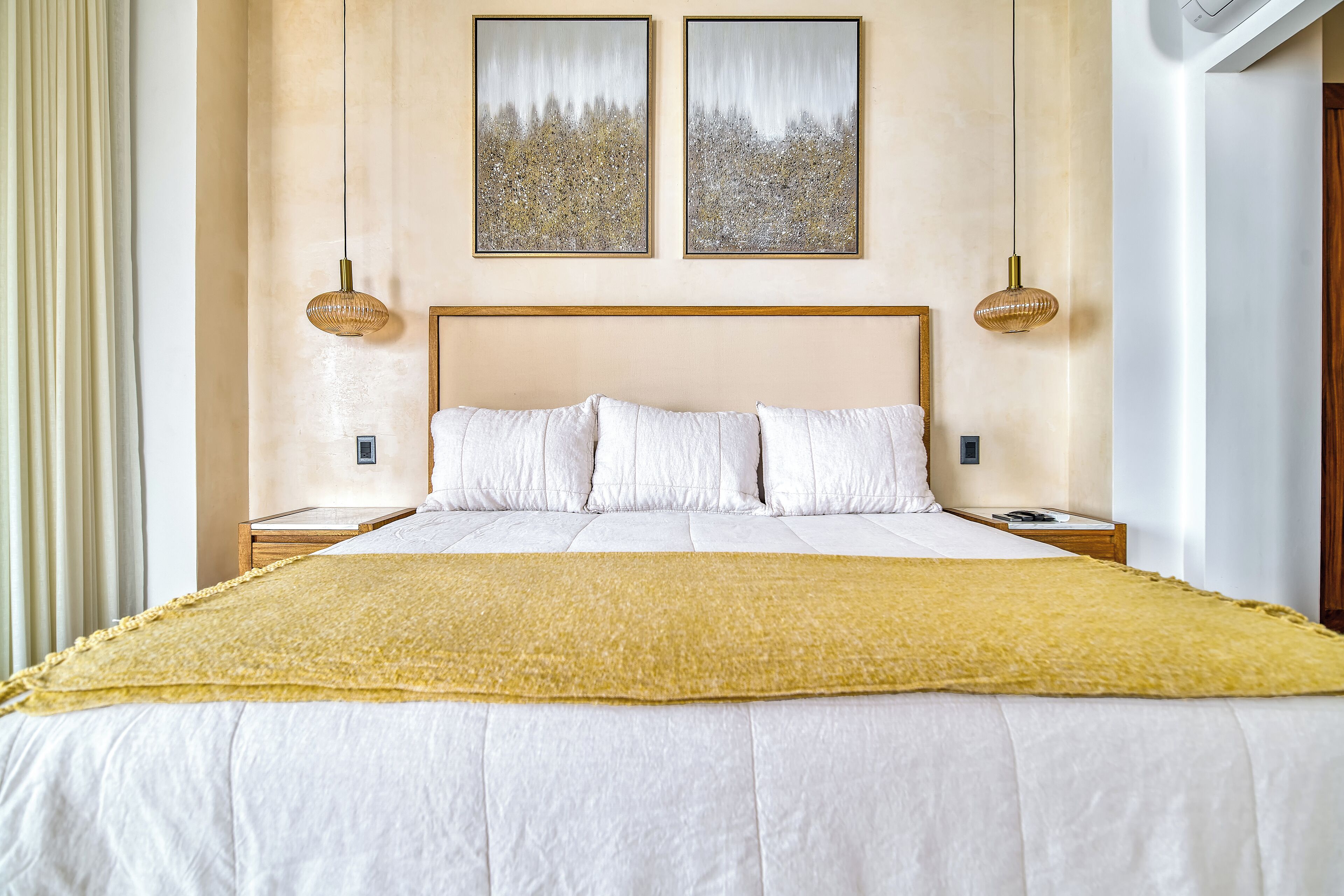 Un dormitorio con una cama grande, dos mesitas de noche, un cabecero y dos lámparas de pared.
